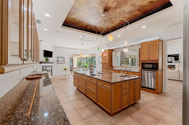 kitchen with black appliances, sink, a tray ceiling, a spacious island, and decorative light fixtures