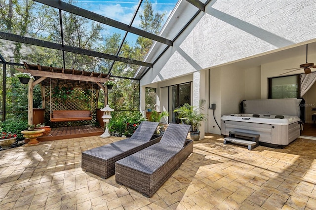 view of patio featuring a hot tub, glass enclosure, and ceiling fan