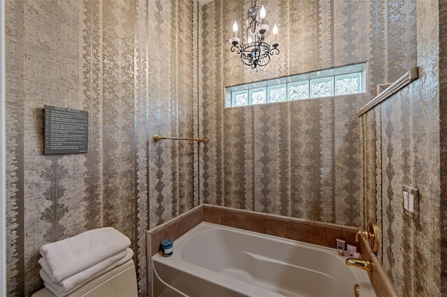 bathroom featuring a chandelier, a washtub, and toilet