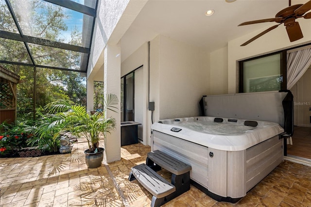 view of patio / terrace featuring a lanai, ceiling fan, and a hot tub