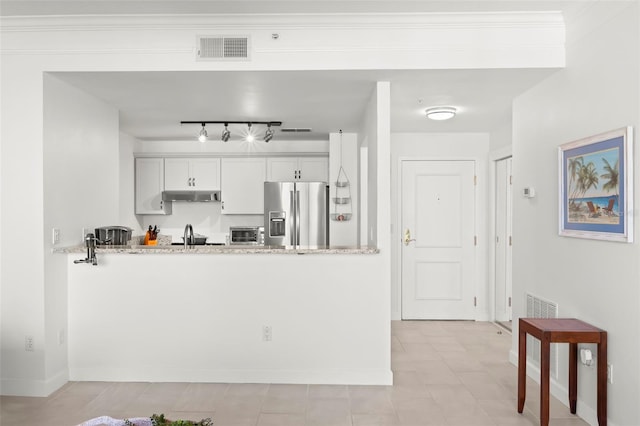 kitchen featuring kitchen peninsula, sink, light stone countertops, white cabinetry, and stainless steel fridge