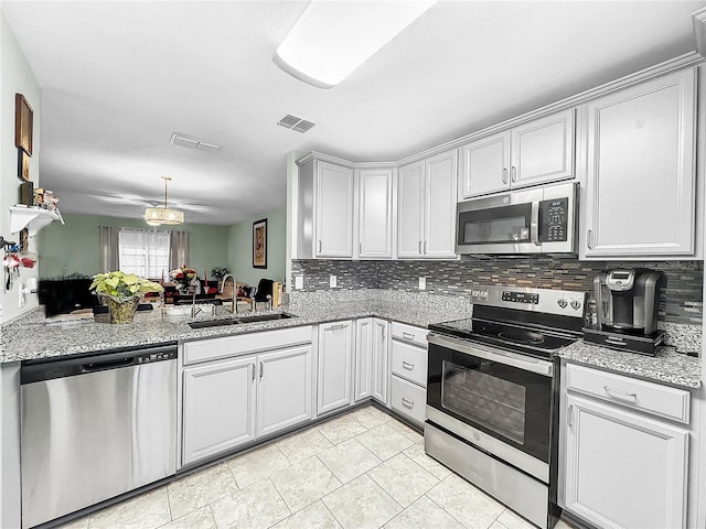 kitchen featuring kitchen peninsula, sink, light stone counters, and stainless steel appliances