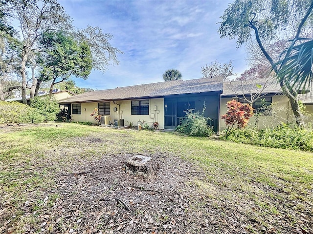 rear view of house featuring central AC unit and a yard