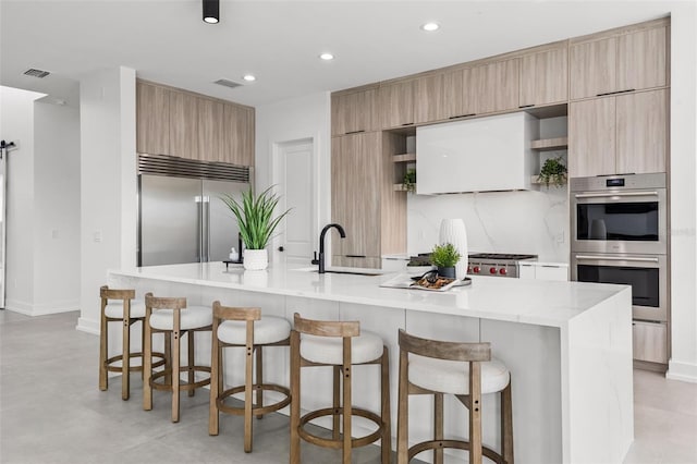 kitchen featuring appliances with stainless steel finishes, tasteful backsplash, sink, a kitchen bar, and a spacious island