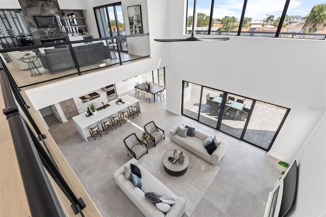 living room with ceiling fan, plenty of natural light, and concrete flooring