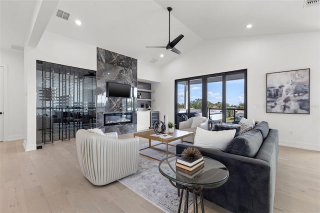 living room featuring wine cooler, ceiling fan, a premium fireplace, and light wood-type flooring