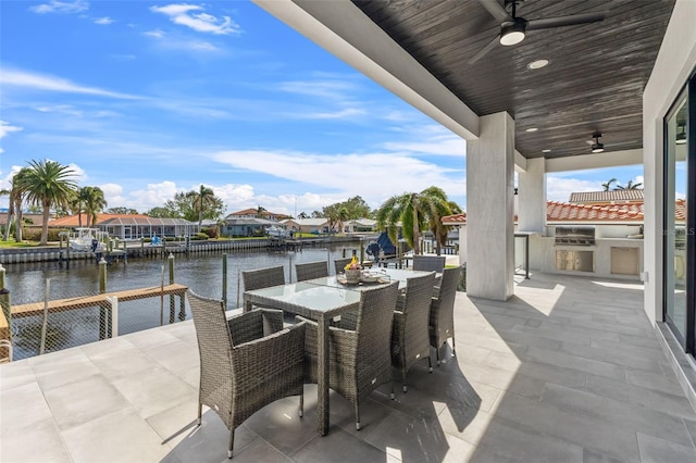 view of patio / terrace featuring a grill, exterior kitchen, ceiling fan, and a water view