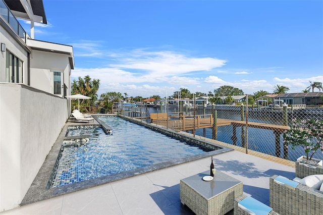 view of swimming pool featuring a patio, a water view, and a dock