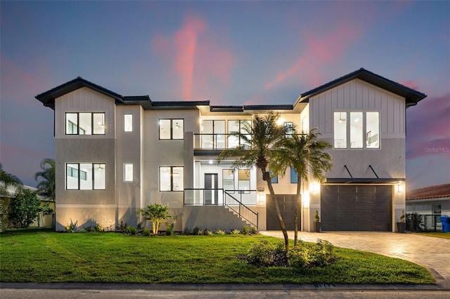 view of front facade with stucco siding, a lawn, decorative driveway, a garage, and a balcony