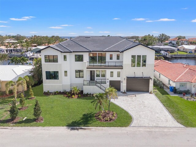 view of front of home featuring a front lawn, a residential view, decorative driveway, a balcony, and an attached garage