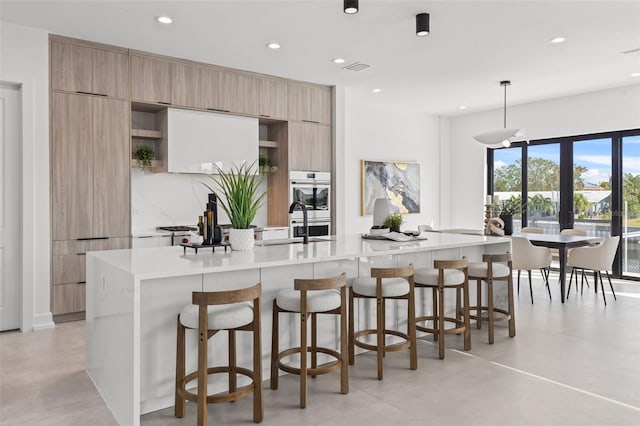 kitchen featuring a spacious island, a kitchen bar, light countertops, recessed lighting, and modern cabinets