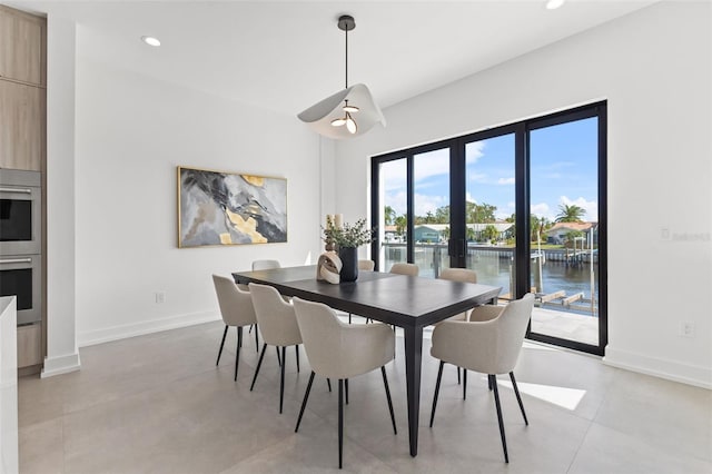 dining area with recessed lighting, french doors, baseboards, and a water view