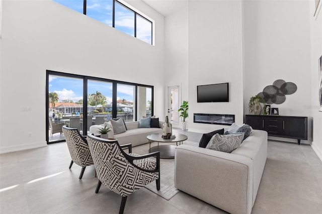 living area with a glass covered fireplace, a high ceiling, and baseboards