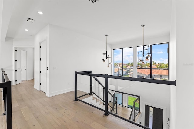 corridor featuring baseboards, recessed lighting, a notable chandelier, an upstairs landing, and light wood-type flooring