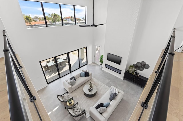 living room with concrete flooring, a towering ceiling, and ceiling fan