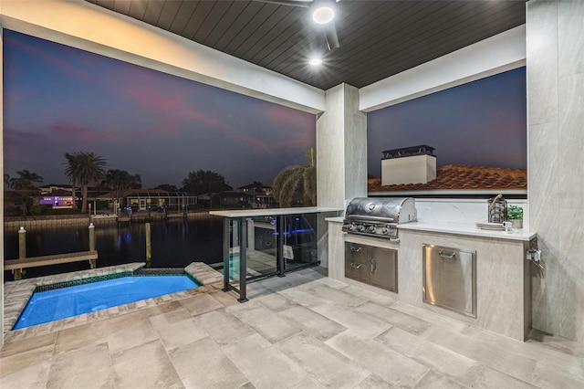 view of patio featuring area for grilling, a water view, and an outdoor kitchen