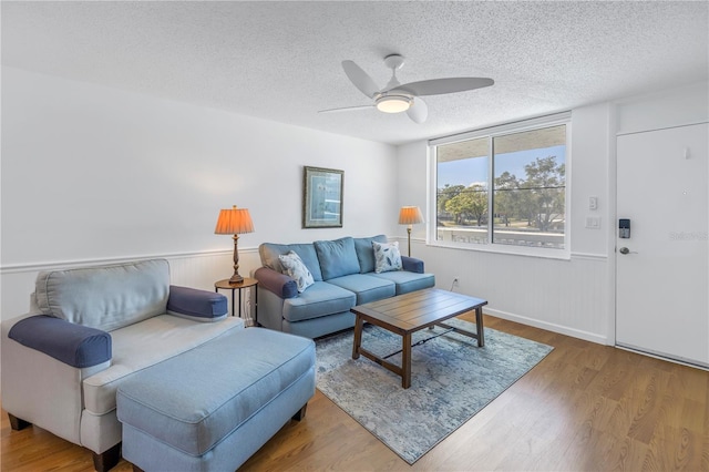 living room with hardwood / wood-style floors, ceiling fan, and a textured ceiling