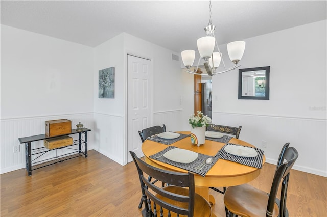 dining space with light hardwood / wood-style flooring and a chandelier