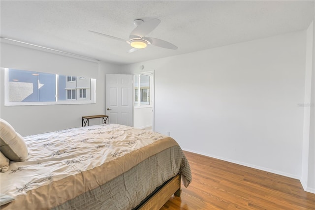 bedroom with ceiling fan, wood-type flooring, and a textured ceiling