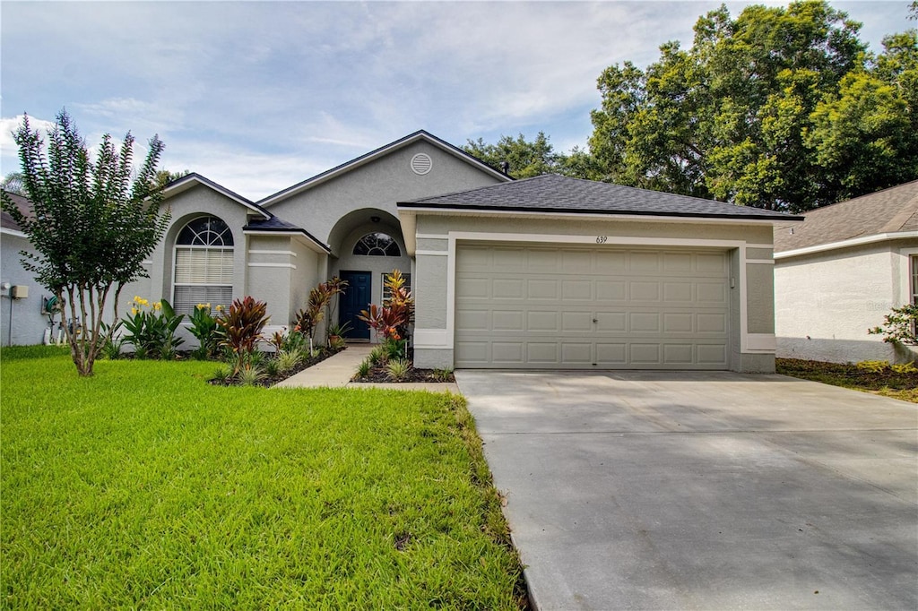 ranch-style home featuring a garage and a front lawn