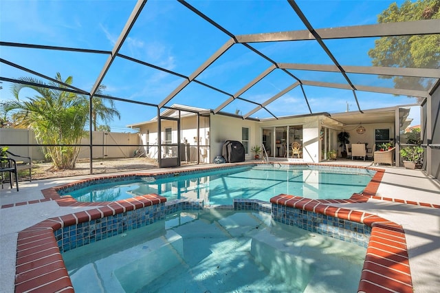 view of pool featuring a patio area, glass enclosure, and an in ground hot tub