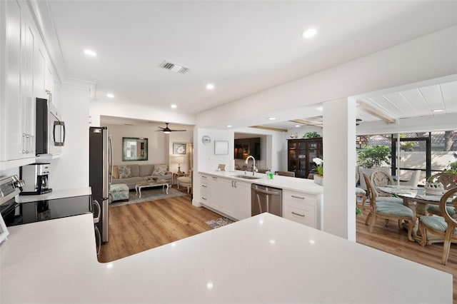 kitchen with visible vents, appliances with stainless steel finishes, open floor plan, light countertops, and light wood-style floors