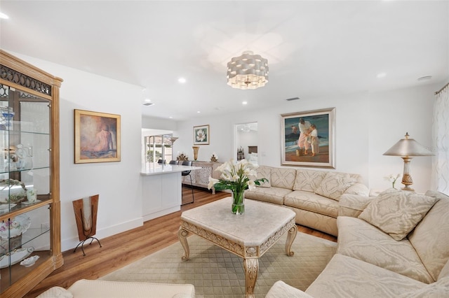 living room with recessed lighting, visible vents, baseboards, and wood finished floors