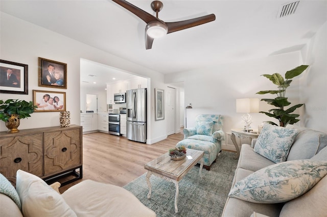 living room with visible vents, baseboards, light wood-style flooring, and a ceiling fan