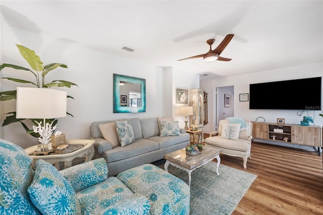 living room featuring a ceiling fan, visible vents, and wood finished floors