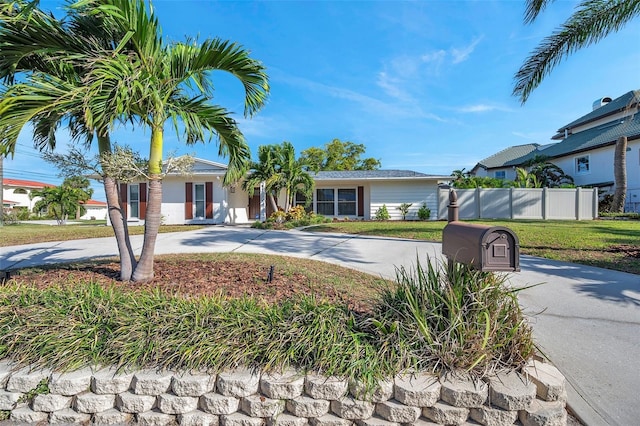 single story home with driveway, fence, and a front yard