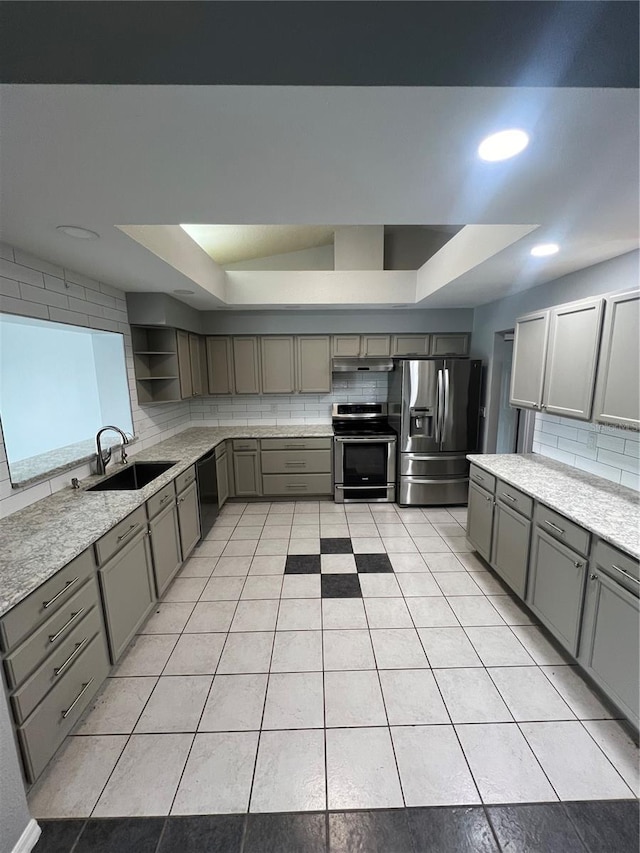 kitchen with a raised ceiling, sink, backsplash, and appliances with stainless steel finishes