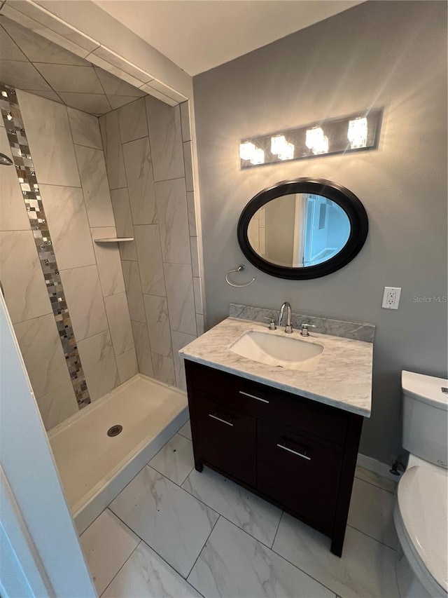 bathroom featuring toilet, vanity, and a tile shower