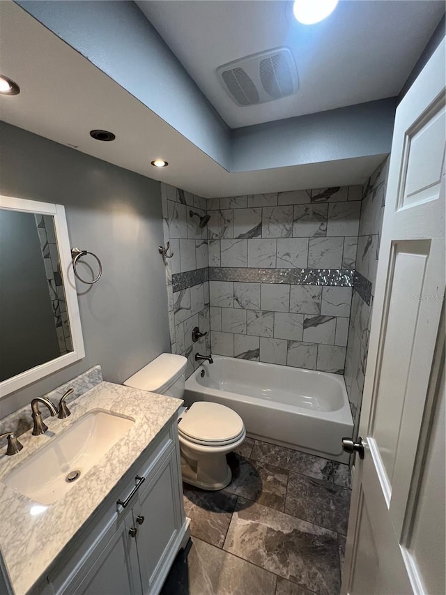 full bathroom featuring vanity, tiled shower / bath combo, and toilet