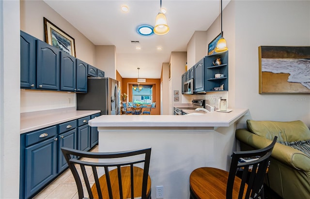 kitchen with kitchen peninsula, a kitchen bar, appliances with stainless steel finishes, and blue cabinets