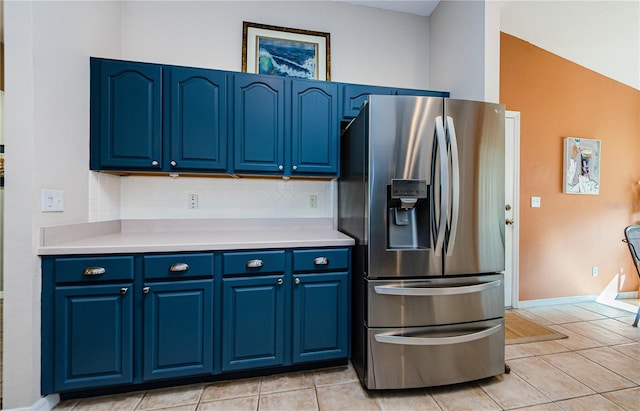 kitchen with tasteful backsplash, blue cabinets, stainless steel refrigerator with ice dispenser, and light tile patterned floors