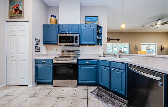 kitchen featuring blue cabinetry, stainless steel appliances, light tile patterned flooring, and pendant lighting