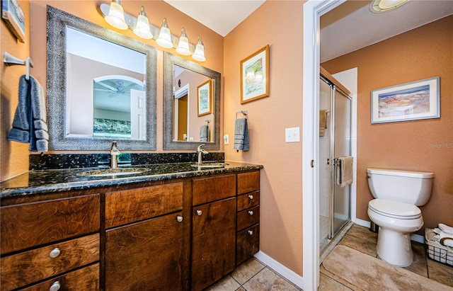 bathroom with tile patterned floors, toilet, vanity, ceiling fan, and a shower with shower door