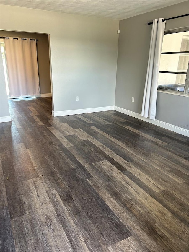 empty room featuring a textured ceiling, dark hardwood / wood-style flooring, and a healthy amount of sunlight