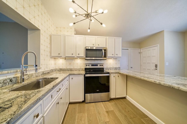 kitchen with appliances with stainless steel finishes, light stone counters, sink, light hardwood / wood-style floors, and white cabinetry