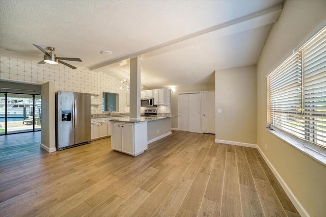 kitchen featuring white cabinets, appliances with stainless steel finishes, lofted ceiling with beams, and light hardwood / wood-style floors