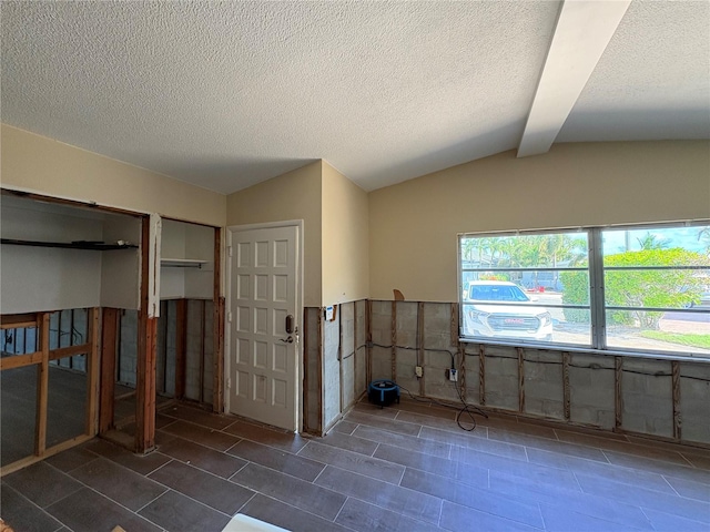 spare room with lofted ceiling with beams and a textured ceiling