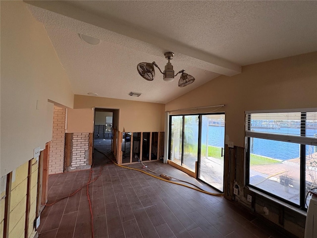 empty room with a water view, lofted ceiling with beams, dark hardwood / wood-style flooring, and a textured ceiling