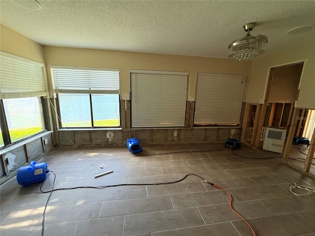 unfurnished room with dark tile patterned floors, a textured ceiling, and a notable chandelier