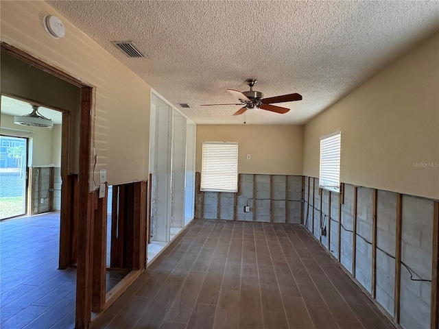 unfurnished room featuring ceiling fan, dark hardwood / wood-style flooring, and a textured ceiling