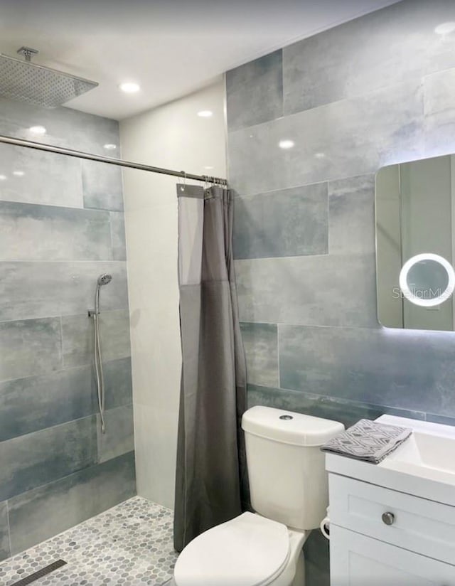 bathroom featuring a shower with shower curtain, vanity, toilet, and tile walls