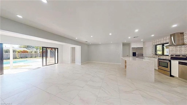 kitchen featuring a center island, white cabinets, sink, backsplash, and appliances with stainless steel finishes