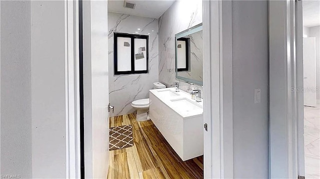 bathroom with hardwood / wood-style floors, vanity, toilet, and tile walls