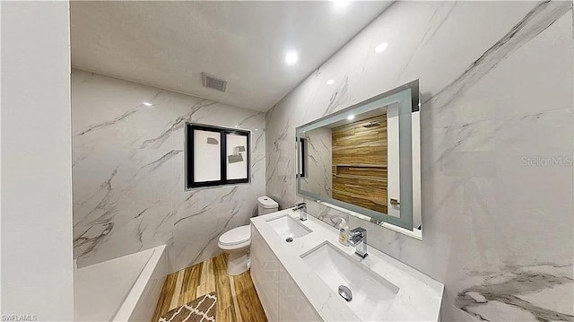 bathroom featuring tile walls, vanity, hardwood / wood-style flooring, and toilet