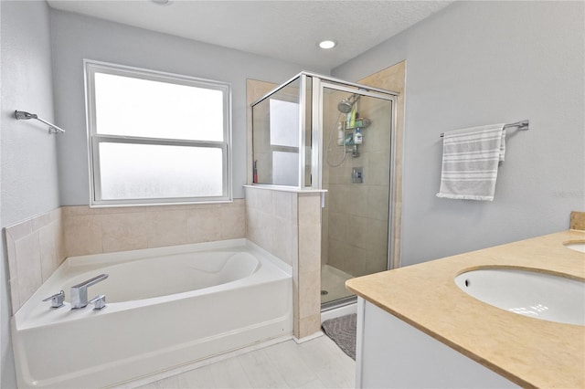 bathroom with plus walk in shower, a textured ceiling, and vanity