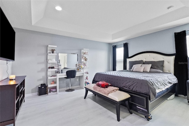 bedroom with a raised ceiling and light hardwood / wood-style floors